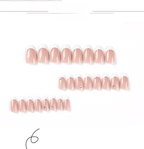 Detailed set of French tip press-on nails in coffin shape with elegant rhinestone accents