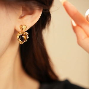 Detail of vintage heart earrings with gold plating and amber-toned tiger eye stones