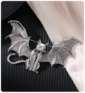 Macro view of vintage silver flying cat brooch showing wings texture and metallic details