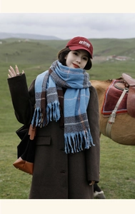 Outdoor shot of blue and brown plaid scarf with tassels and fringe details on a model
