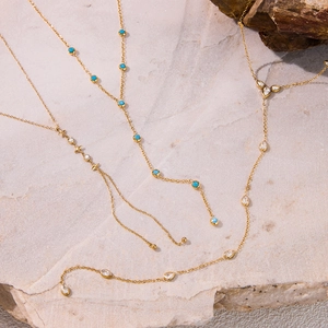 Detailed view of layered 18k gold-plated necklaces with turquoise and crystal pendants