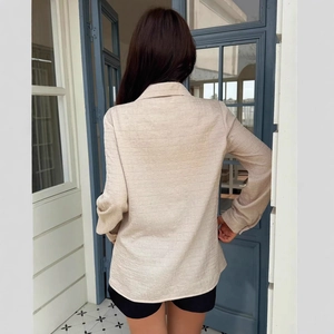 Detail view of beige long sleeve blouse showing horizontal texture on the back material