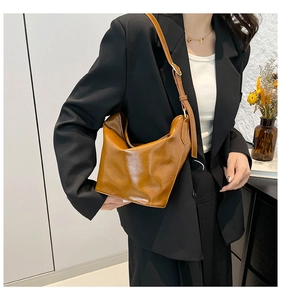 Caramel large PU leather bucket bag featuring glossy wrinkled texture and adjustable strap