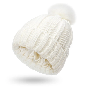 White knit beanie with fluffy pom-pom featuring a protective silk-like satin lining inside