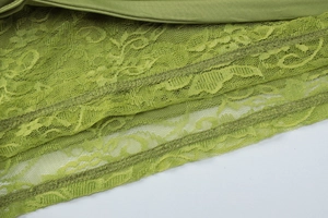 Detailed macro shot of green lace stitching and smooth fabric texture on the dress