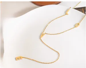 Dettaglio di una collana dorata con ciondoli a lettere LOVE su un piatto di ceramica bianca