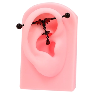 Detail of black industrial barbell piercing with red bat and droplet on silicone ear
