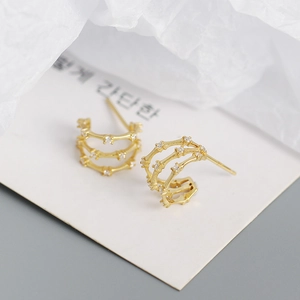 Close-up of triple-layered gold hoop earrings with bamboo design and white zircon stones