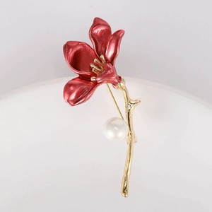 Detailed view of red enamel flower brooch with gold petals and a white pearl accent