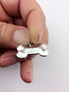 Close-up of a silver bone-shaped pet ID tag pendant with sparkling rhinestones