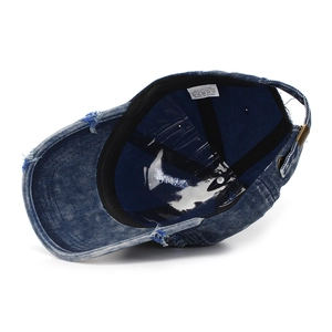 Macro view of distressed denim baseball cap interior showing material tag and stitching