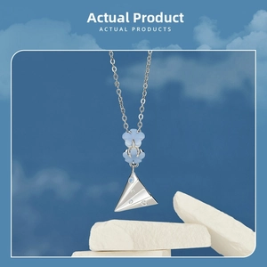 S925 silver paper plane pendant with blue flower beads on white stone background