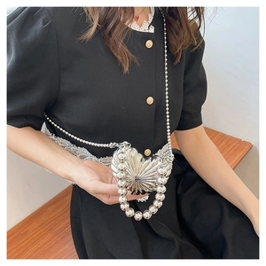 Detail showing metallic heart-shaped handbag with beaded chains on a lace dress