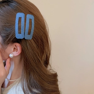 Detail view of navy denim fabric hair clips worn by a model for a stylish casual hair look