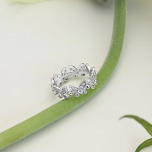Macro shot of a silver butterfly ring with cubic zirconia on a green plant stem