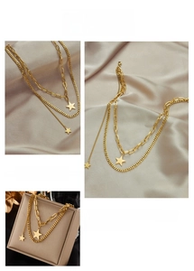 Detail of layered gold titanium steel necklace featuring star pendants and Cuban chain