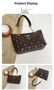 Detail view of dark brown monogram tote bag with gold chain straps and deer charm