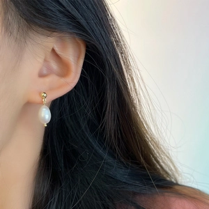 Close-up of model wearing baroque freshwater pearl earrings with gold stud details