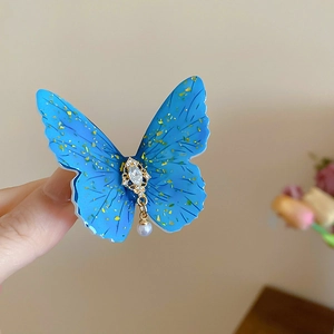 Détail de la pince à cheveux papillon en acrylique bleu avec paillettes et perle