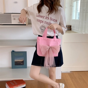 Nahaufnahme einer rosa Canvas-Tasche mit großer Netzschleife, gehalten von einem Modell
