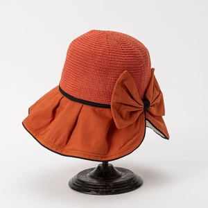 Detail of burnt orange sun hat featuring a knit crown and large decorative bow