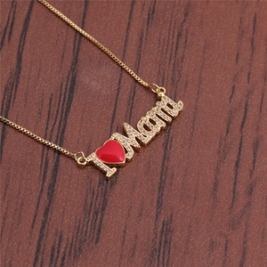 Golden Mama necklace with red heart pendant and cubic zirconia on wooden background