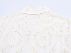 Macro shot of white eyelet embroidery fabric on a minimalist summer shirt dress