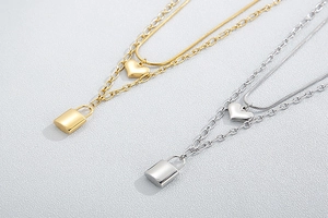 Close-up of dual-layer stainless steel heart and padlock pendant necklace in gold and silver