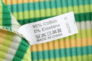 Gros plan de l'étiquette d'entretien du string en coton à rayures vertes et jaunes, taille S