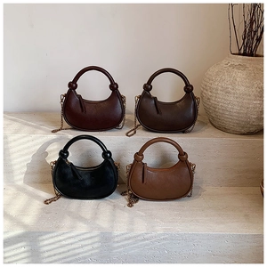 Chic leather crescent bags in four colors arranged on stone steps with gold chain straps