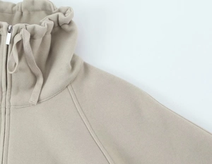 Détail du sweat-shirt kaki clair avec col montant, cordon de serrage et zip métallique