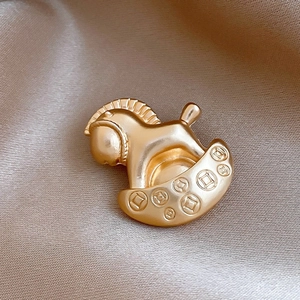 Macro detail of a vintage golden rocking horse brooch with ancient coin relief pattern