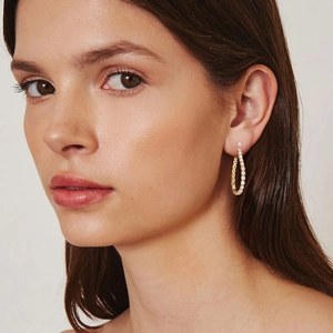Elegante goldene Tropfenohrringe mit weißen Zirkonia-Kristallen, getragen am Model