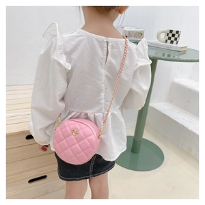 Close-up of pink round quilted bag with golden flower and metal chain on a model