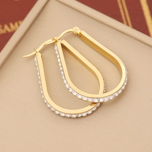 Macro detail of gold hoop earrings with sparkling white crystals on jewelry box