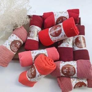 Detailed texture of pleated cotton scarves in various red shades with floral paper bands