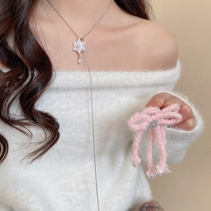 Elegant snowflake pearl necklace and bow hair accessory set on a model in white sweater