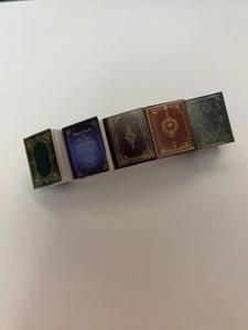Detail view showing five colorful miniature book hair clips in dark red, blue and green