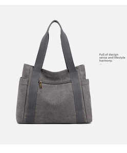 Detail of grey canvas tote bag featuring front zipper pocket and side compartments