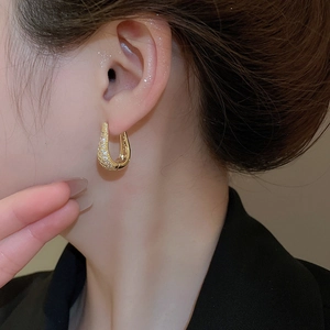 Gros plan de boucles d'oreilles en U dorées avec zircons pour un style élégant et chic