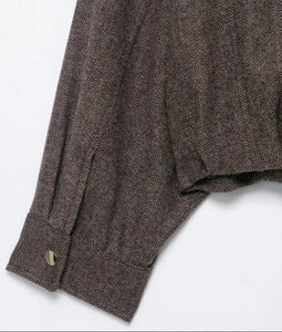 Detail view of brown herringbone wool jacket cuff featuring a vintage metal button