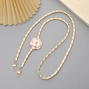 Detail of camellia flower accessory on gold chain and woven leather phone strap