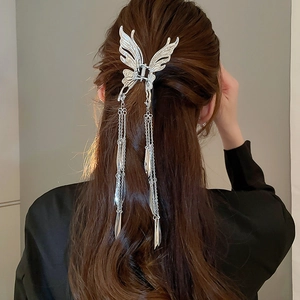 Detail of silver butterfly hair claw with long metal tassels on elegant hairstyle