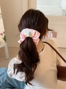 Pink satin scrunchie featuring delicate strawberry embroidery worn on a ponytail