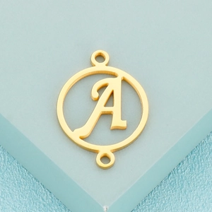 Macro shot of gold stainless steel circular pendant with a hollow letter A design