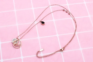 Detail of rose gold double-layer necklace with peace pendant and black teardrop stone