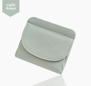 Close-up of light green pebble leather card holder with secure flap and visible texture