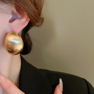 Close-up of stylish chunky gold geometric earrings on model with metallic finish