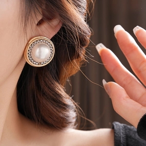 Gros plan détaillé d'une boucle d'oreille perle vintage avec bordure en chaîne bicolore