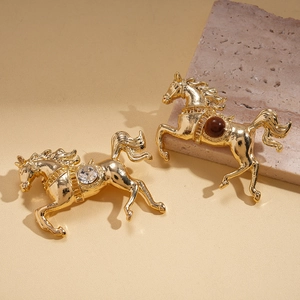 Vintage gold horse brooches with diamond and brown resin stones on stone background